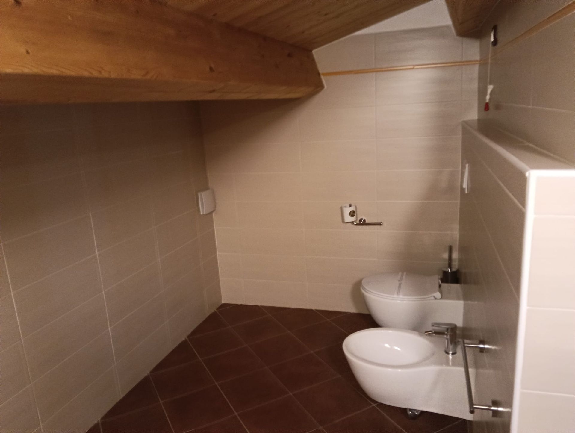 Bagno con due WC bianchi su pavimento piastrellato; soffitto con travi in legno.