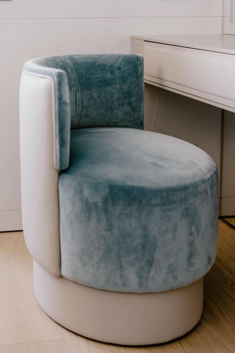 Una sedia blu e bianca è seduta accanto a una scrivania bianca.