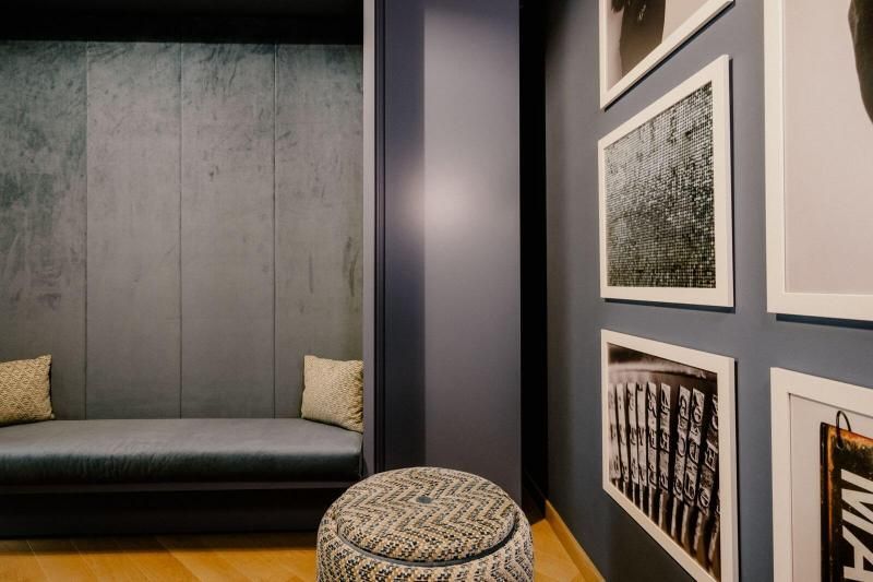 Una stanza con un divano, un pouf e quadri alle pareti.