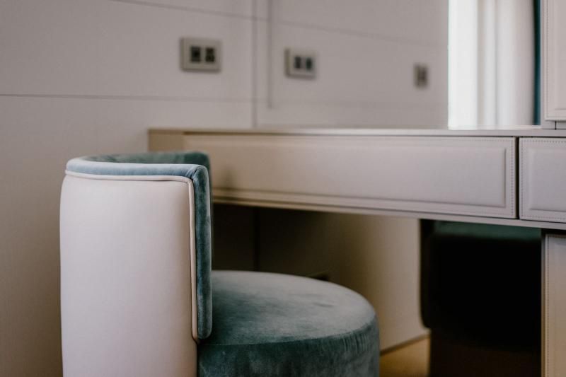 Una sedia è seduta accanto a una toletta in una stanza.