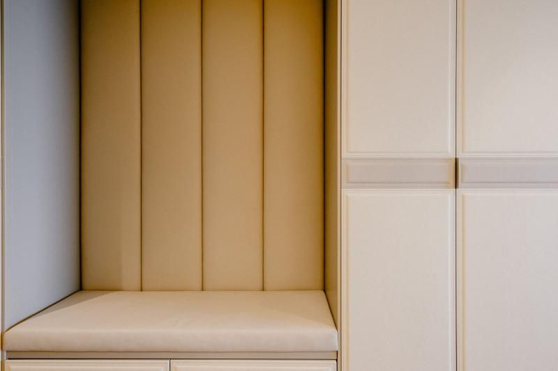 C'è una panca nell'angolo della stanza accanto ad un armadio.