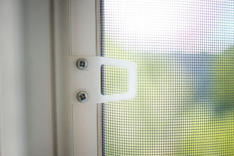 Un primo piano di una porta con zanzariera con maniglia bianca.