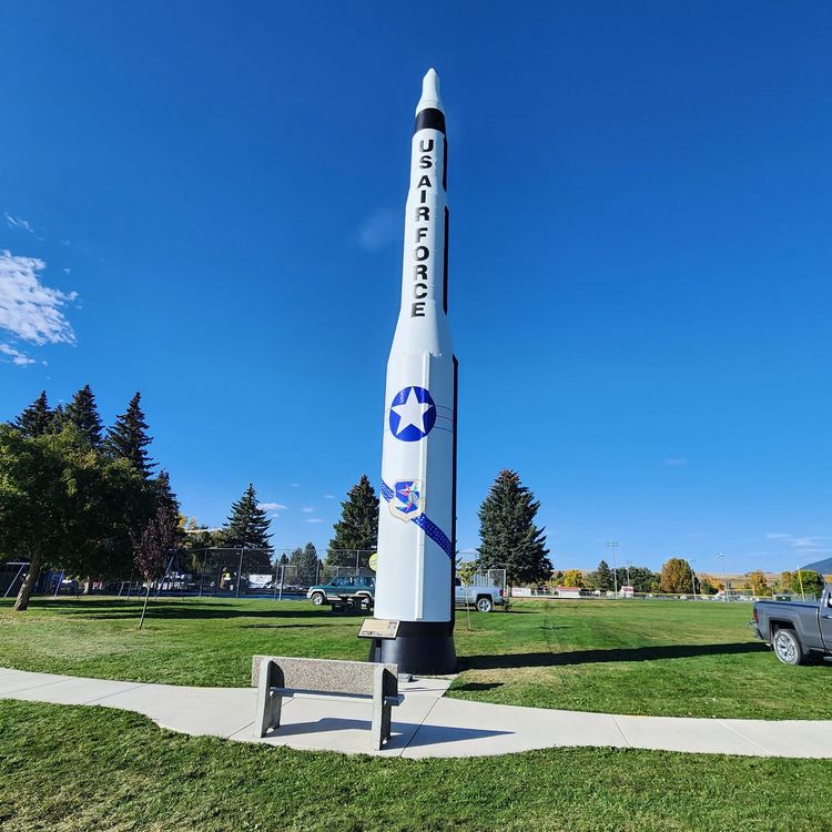 Person on a scaffolding installs blue and white letters on a sign.