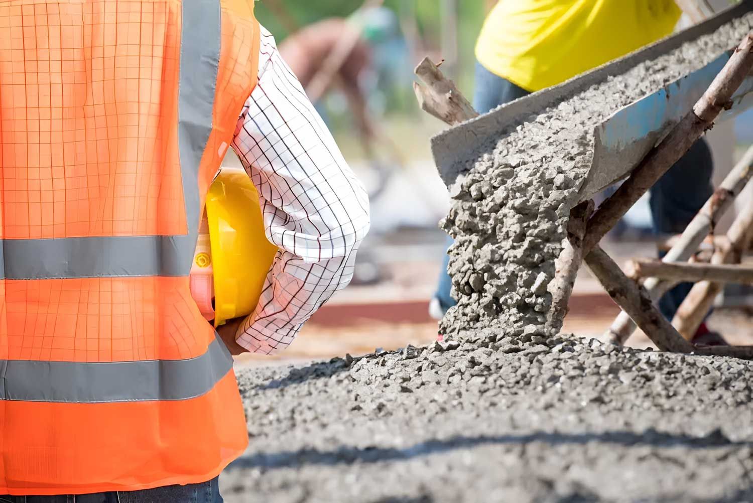Construction Worker Standing Next To A Wheelbarrow Filled With Concrete — Ingham Concrete–Icon in Ingham, QLD