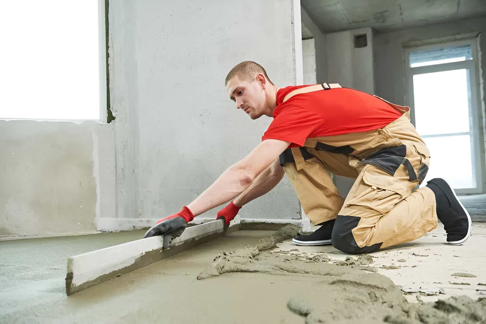 A Man Is Kneeling Down And Spreading Concrete On The Floor — Ingham Concrete–Icon in Cardwell, QLD
