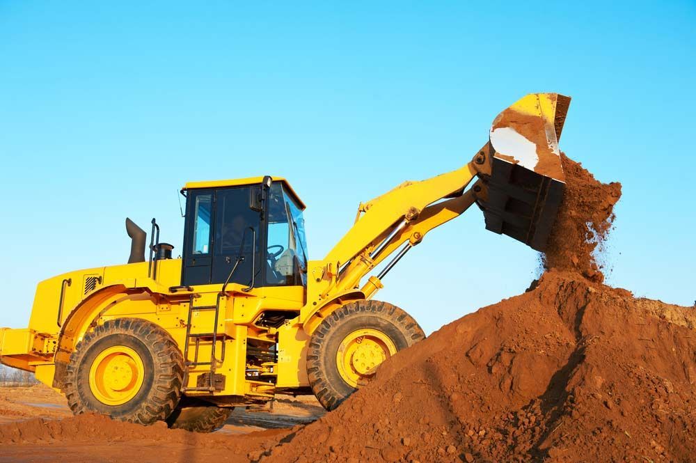 A Yellow Bulldozer Is Loading Dirt Into A Pile — Ingham Concrete–Icon in Cardwell, QLD