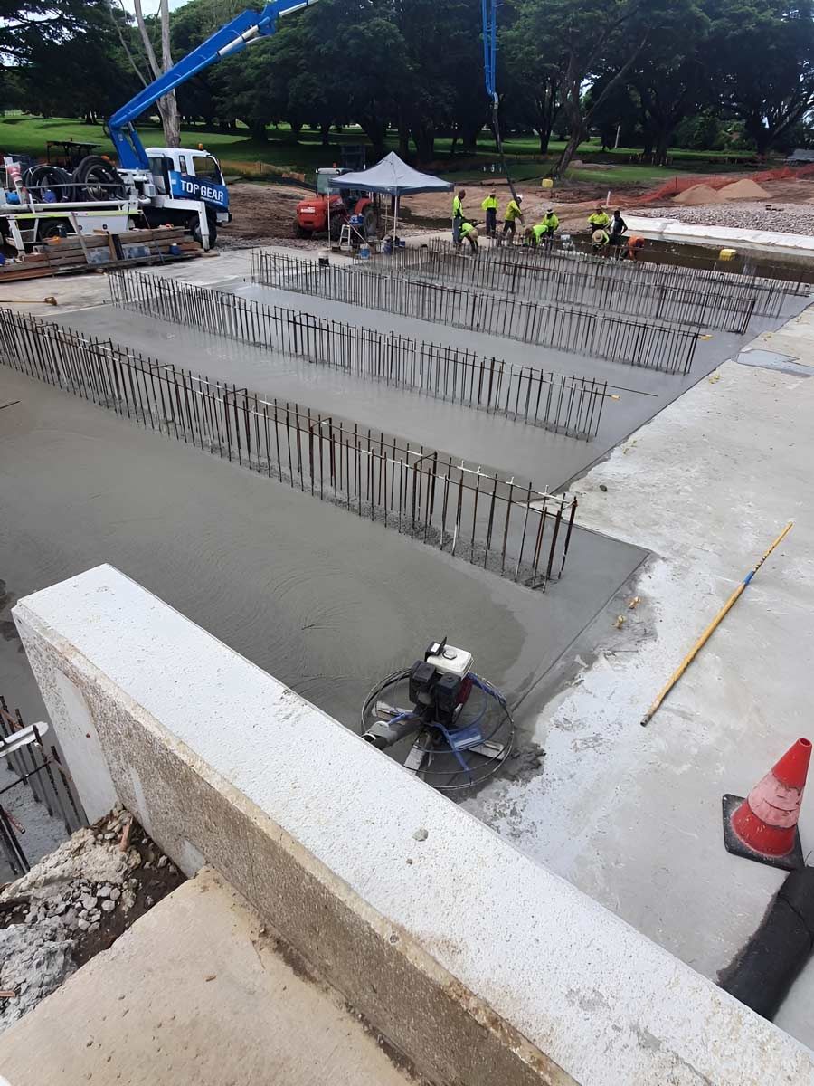 A Team Of Construction Workers Is Laying Concrete For The Flooring — Ingham Concrete–Icon in Ingham, QLD