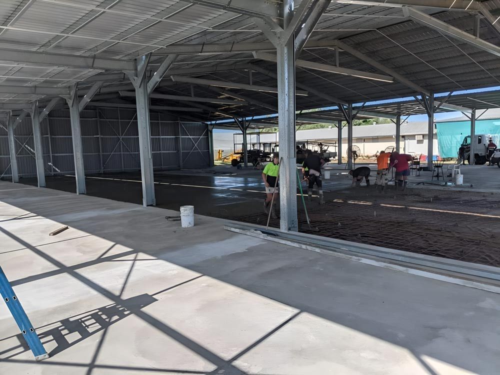 A Group Of People Are Working On A Concrete Floor Under A Roof — Ingham Concrete–Icon in Cardwell, QLD