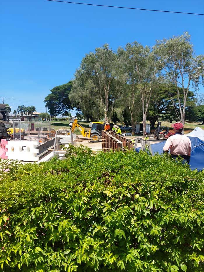 A Group Of People Are Standing In Front Of A Construction Site — Ingham Concrete–Icon in Ingham, QLD