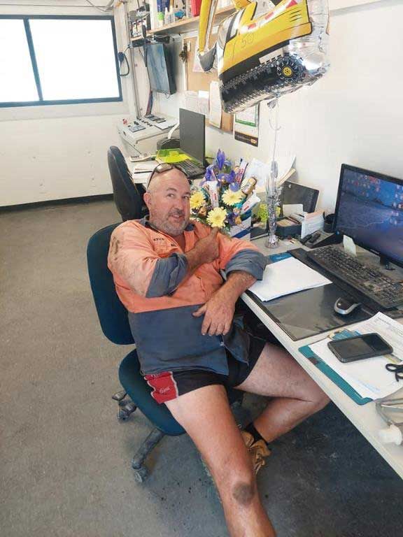A Man Is Sitting At A Desk With His Legs Crossed — Ingham Concrete–Icon in Ingham, QLD