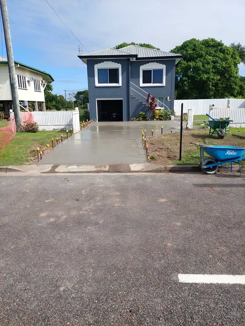 A House With A Concrete Driveway And A Wheelbarrow In Front Of It — Ingham Concrete–Icon in Ingham, QLD