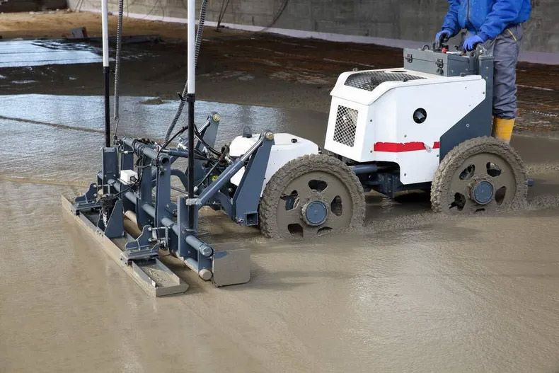 A Man Is Using A Machine To Level A Concrete Floor — Ingham Concrete–Icon in Cardwell, QLD