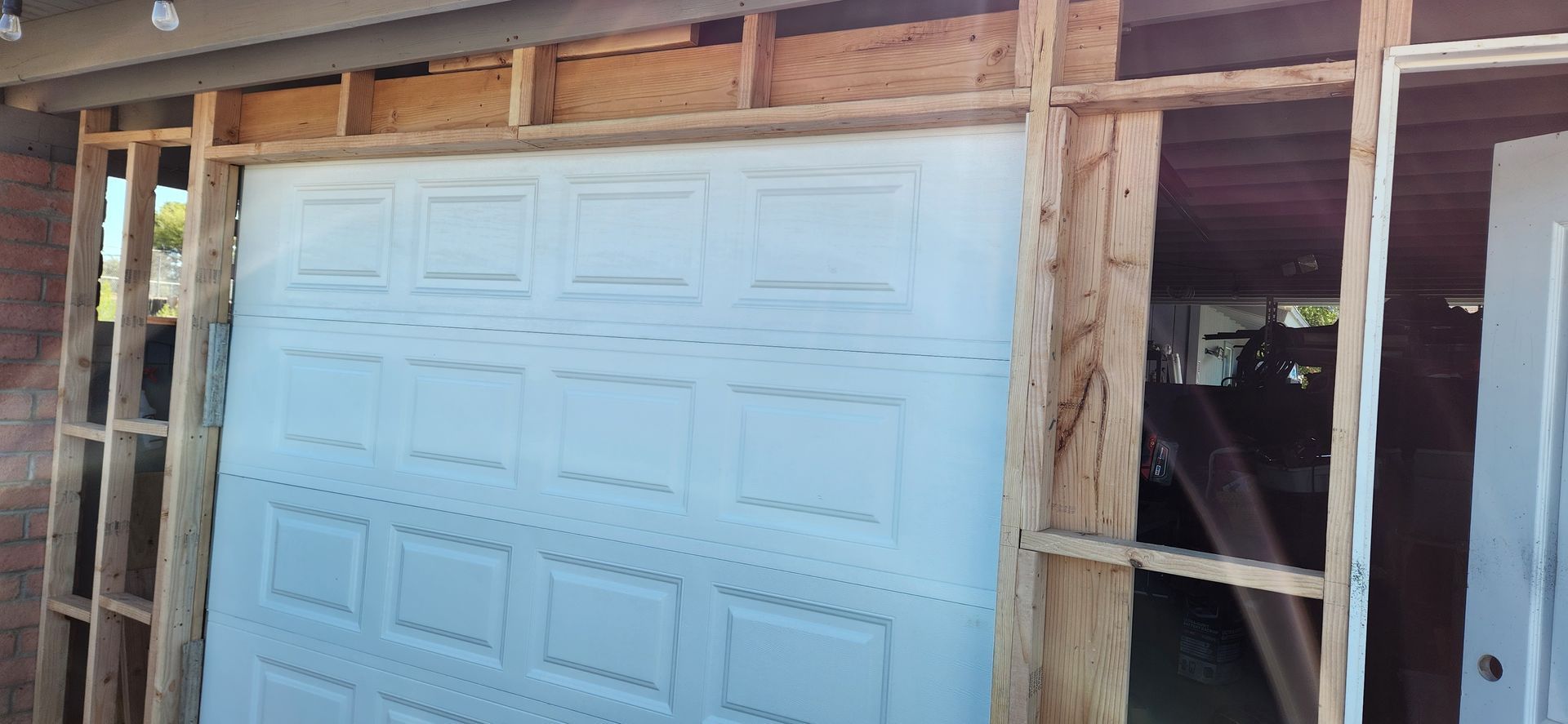 A garage door is being installed in a house under construction.