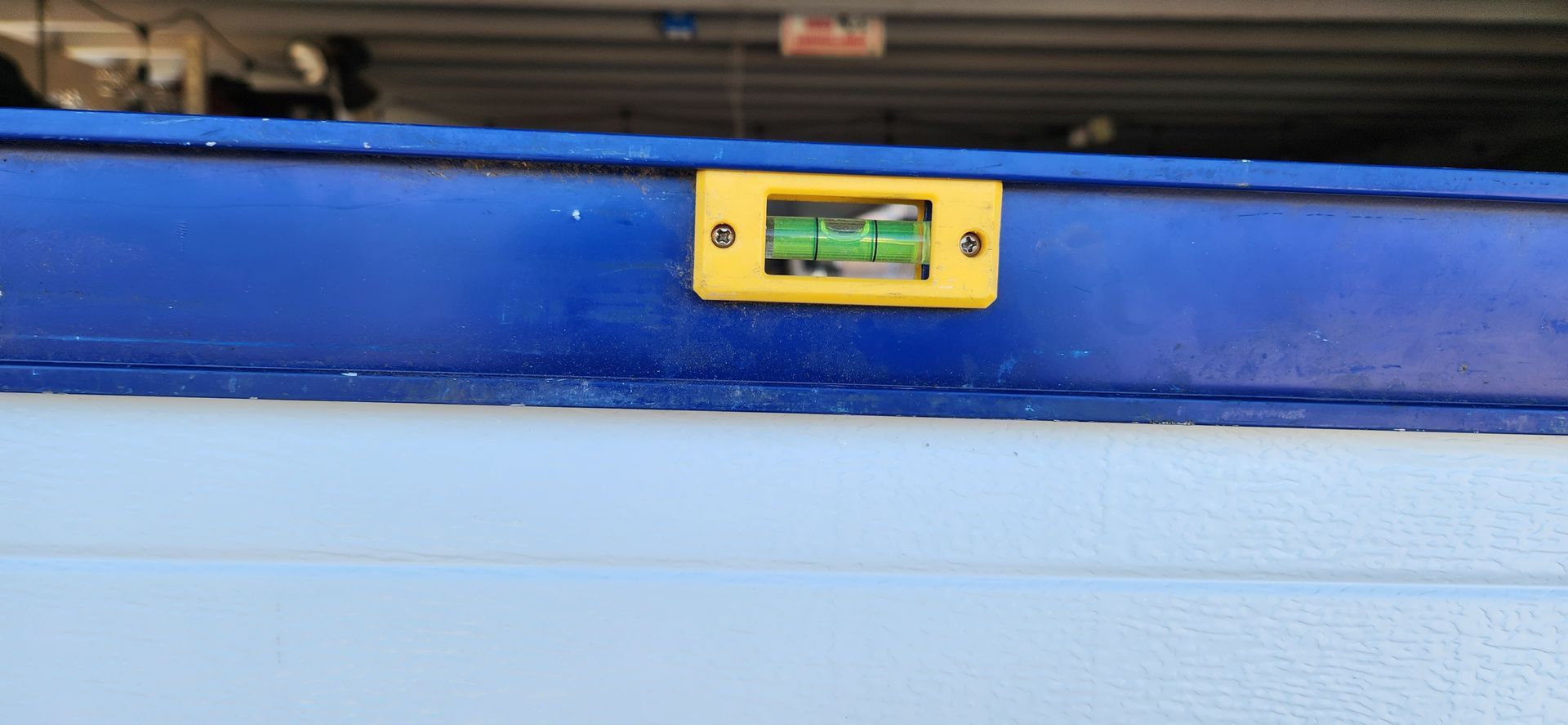 A yellow level is sitting on top of a blue wall.