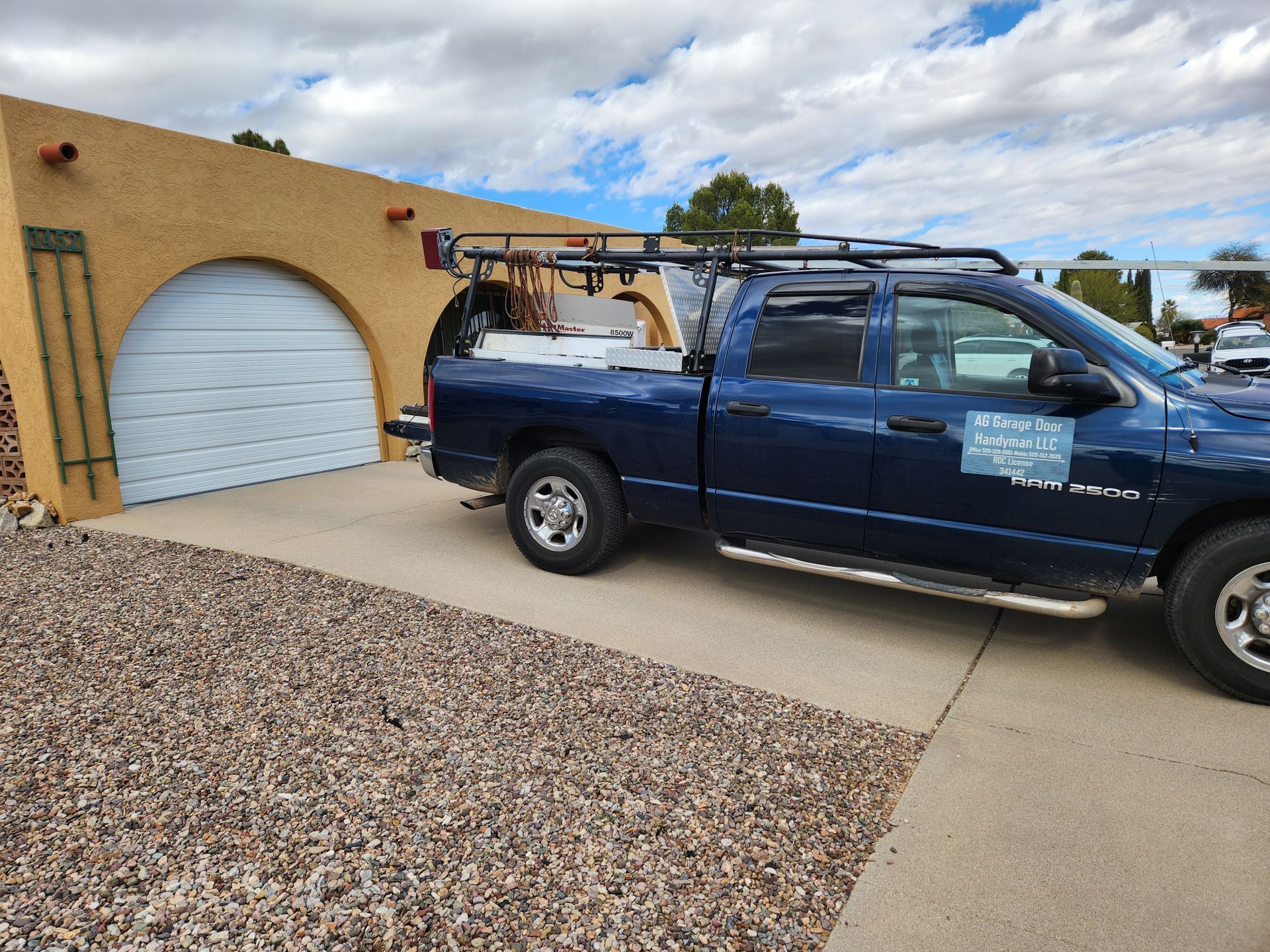 A blue truck is parked in front of a garage door.