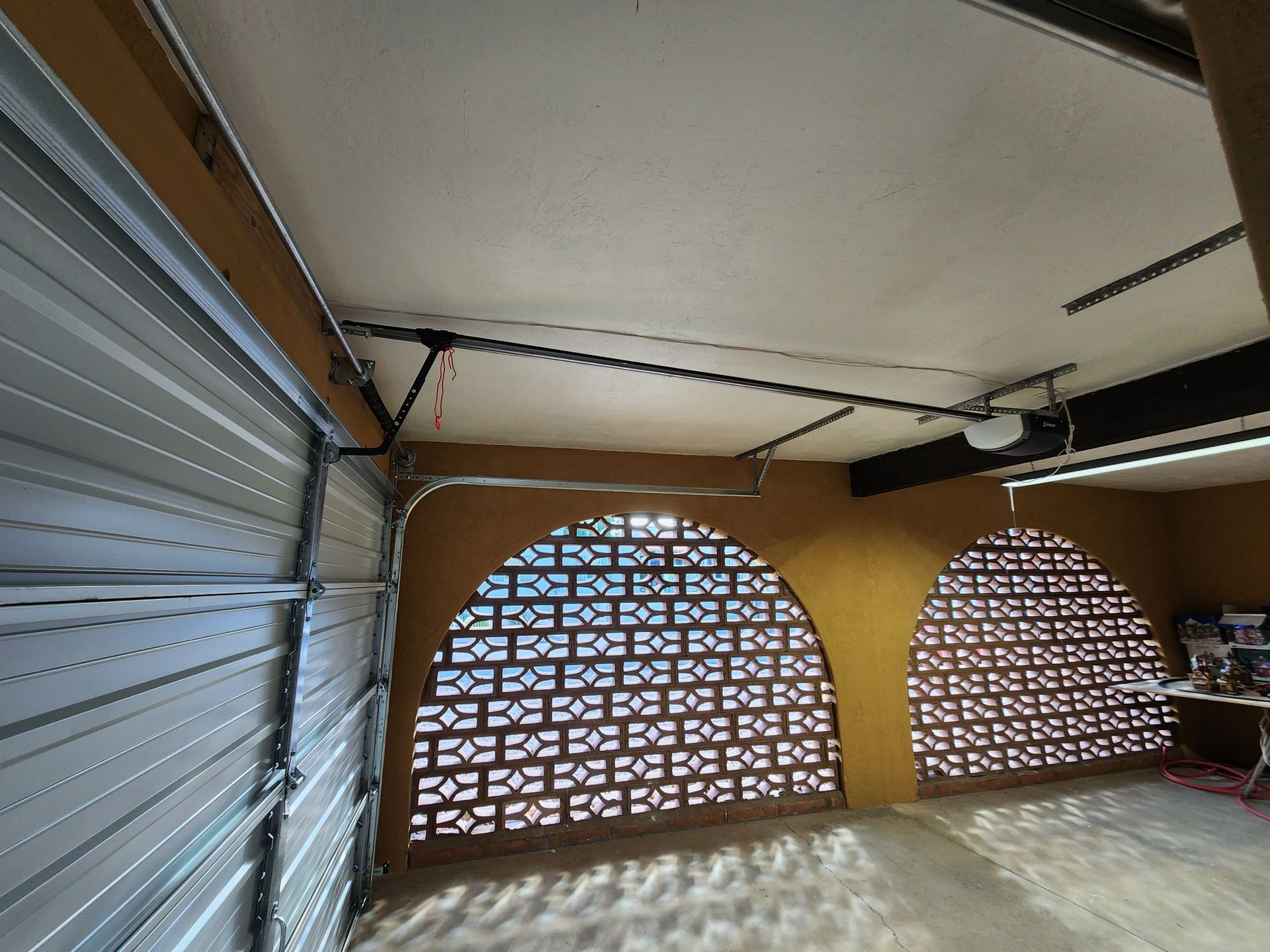 A garage with a garage door open and a ceiling fan.