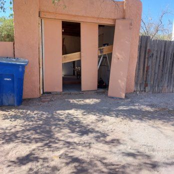 A pink building with a blue trash can in front of it.