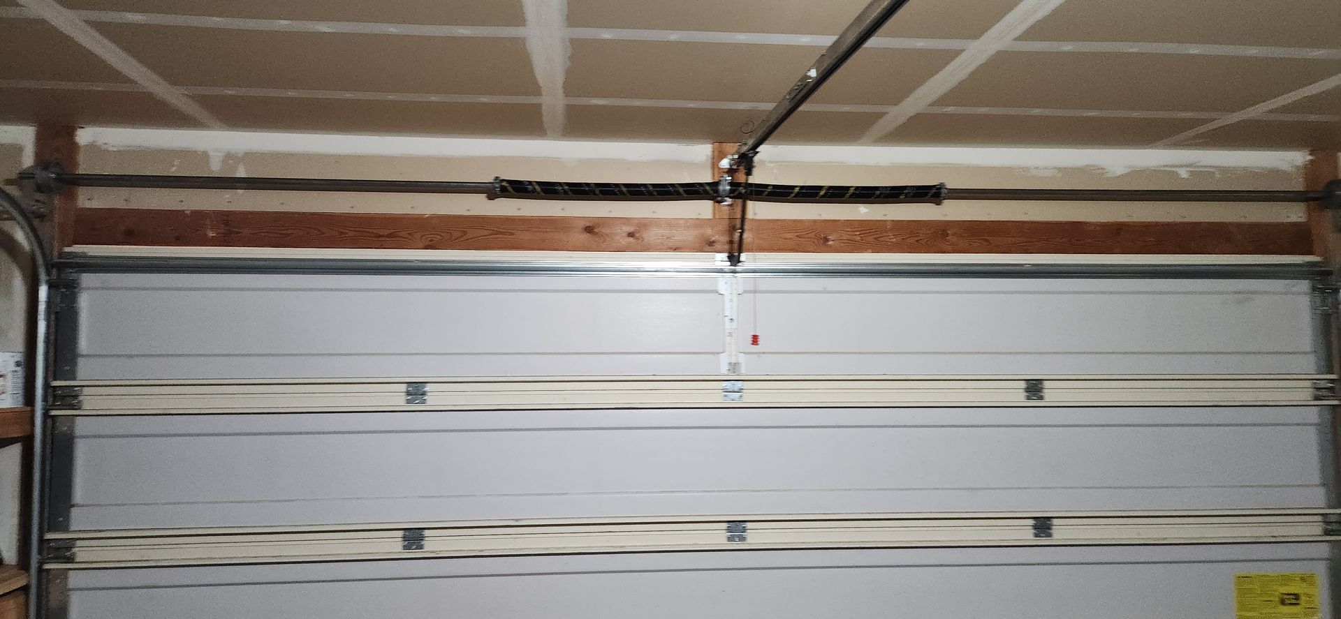 A garage door with the door open and a ceiling in the background.