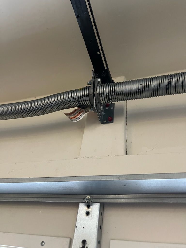 A close up of a garage door spring hanging from the ceiling.