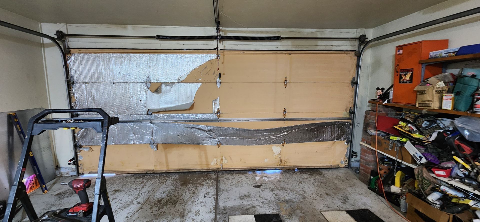A garage with a broken garage door and a lot of tools.