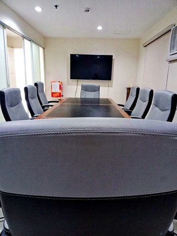 A conference room with a long table and chairs and a flat screen tv.