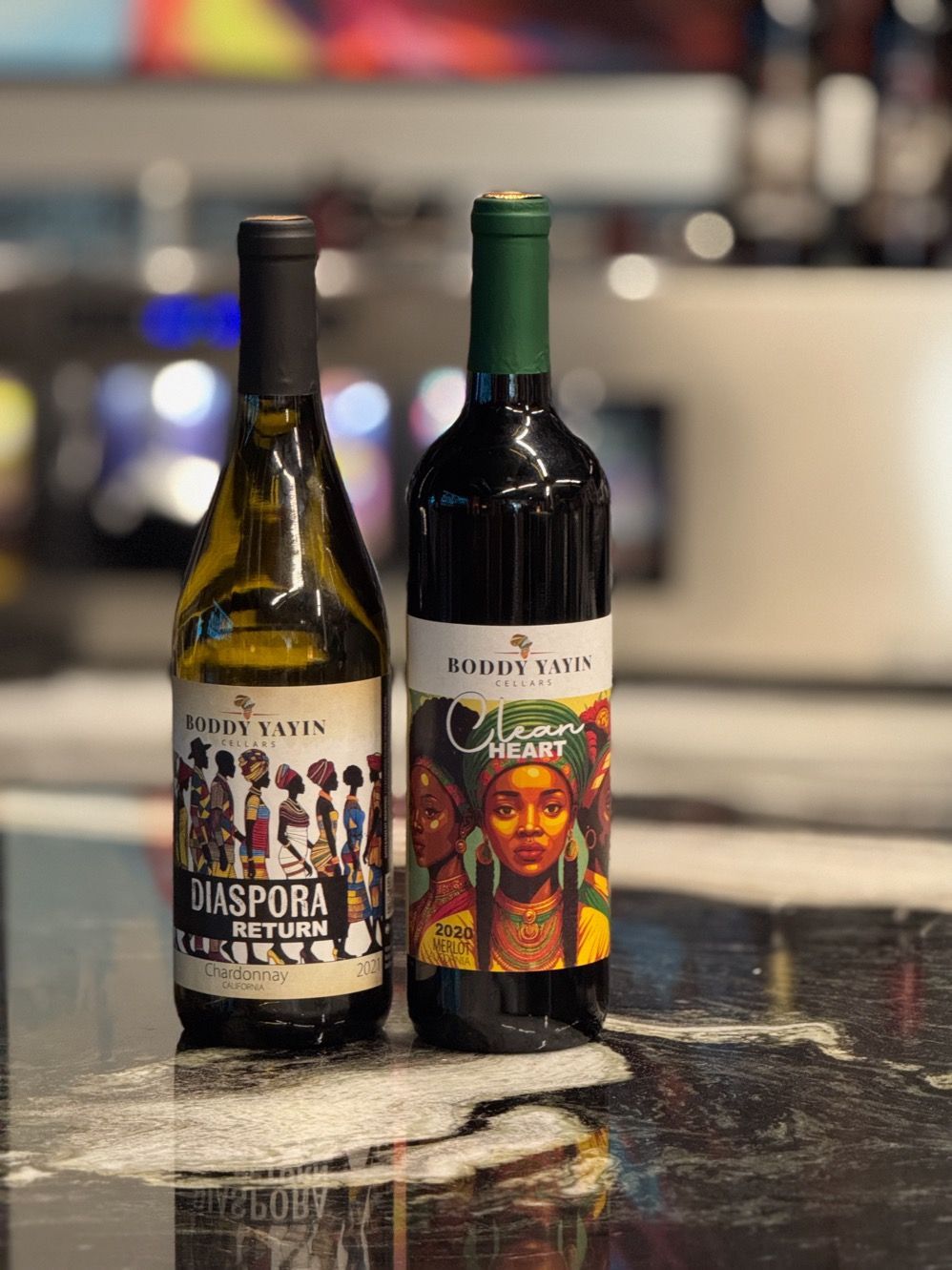 Two bottles of wine are sitting on a counter.