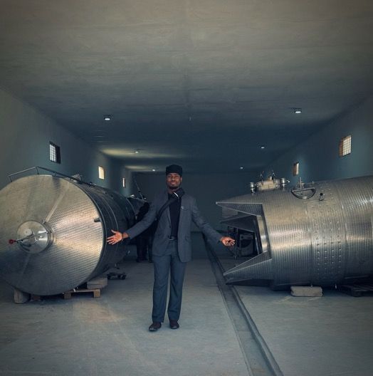 A man in a suit is standing in a room with large metal tanks.