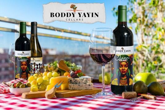 A bottle of boddy yavin wine is sitting on a table next to a glass of wine.