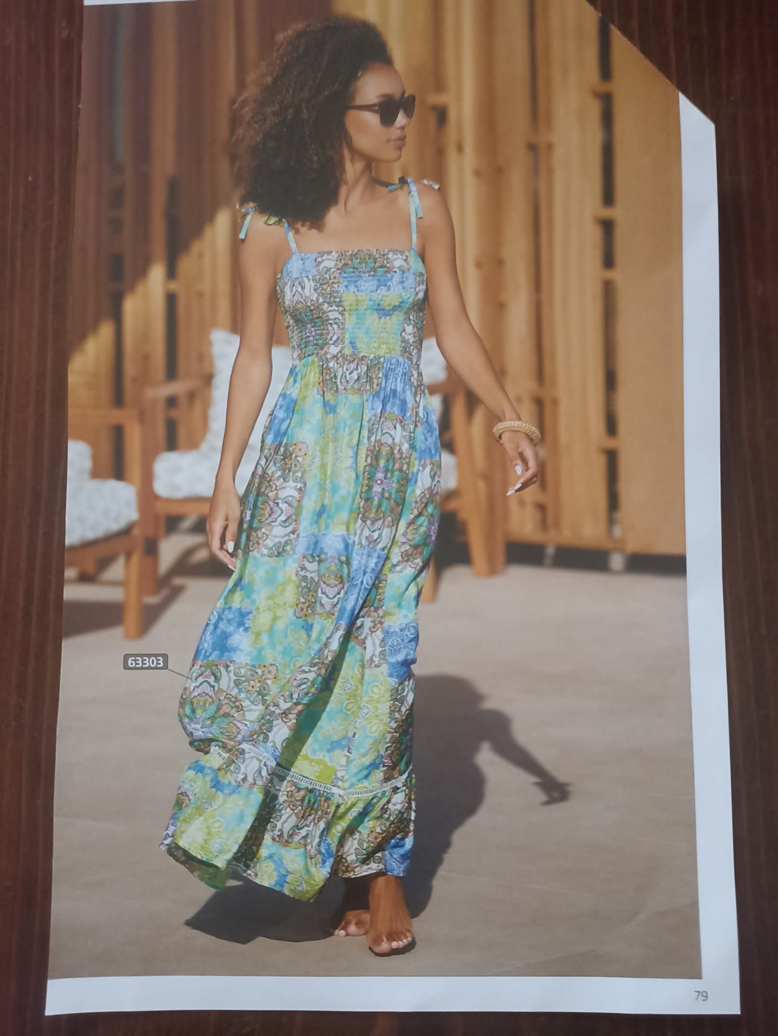 Una donna con un abito lungo floreale e occhiali da sole è all'aperto in una giornata di sole.