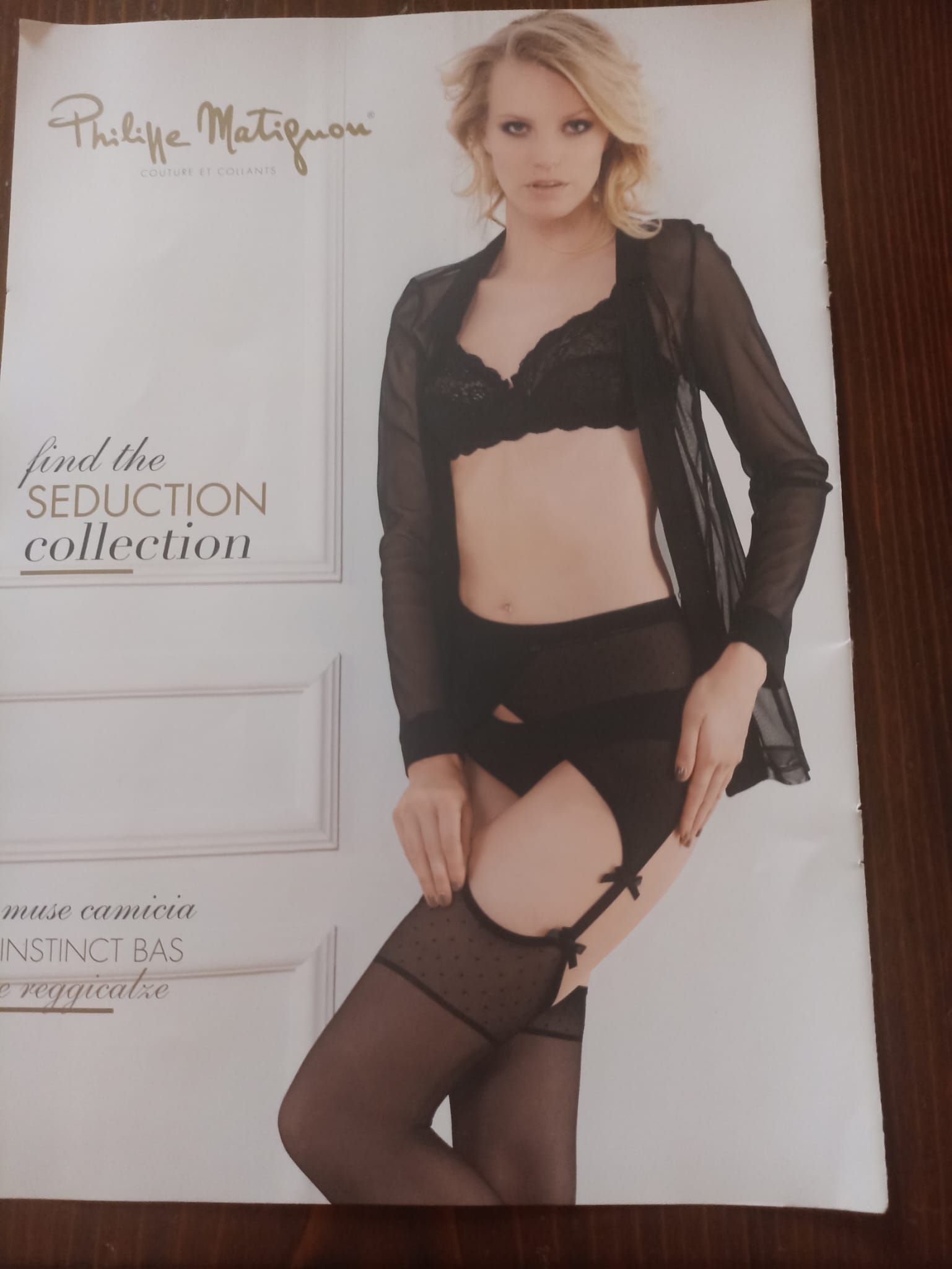 Donna in lingerie nera, vestaglia trasparente, calze e reggicalze, in posa per una pubblicità di lingerie.