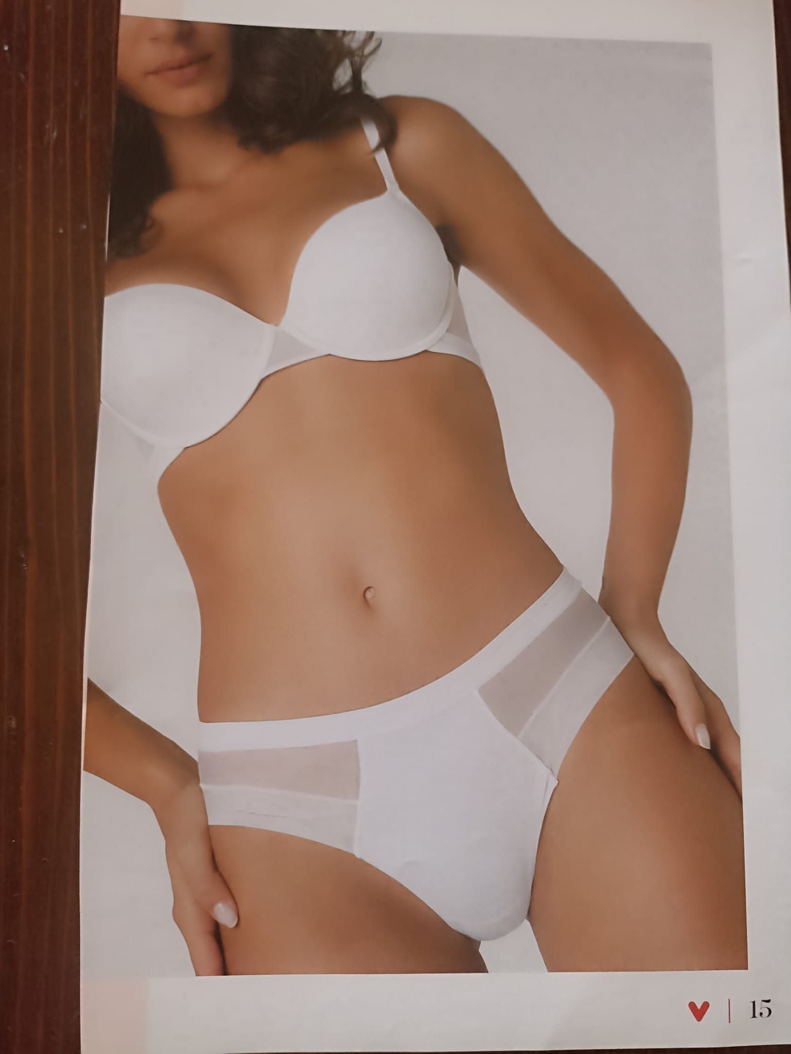 Donna in lingerie bianca, in posa, mani sui fianchi.