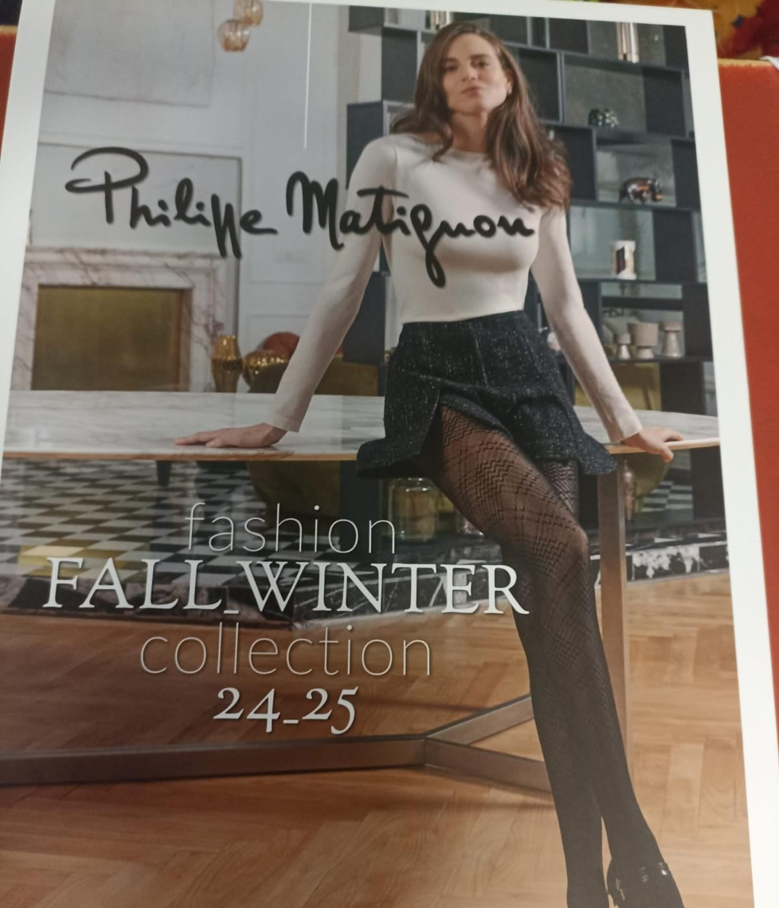 Pubblicità di moda di Philippe Matignon con modella in collant e gonna fantasia. Testo: 