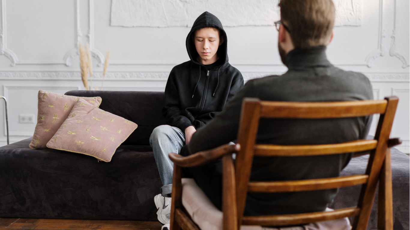 Two people in close conversation. One person clenches hands; the other's hands are open, offering support.