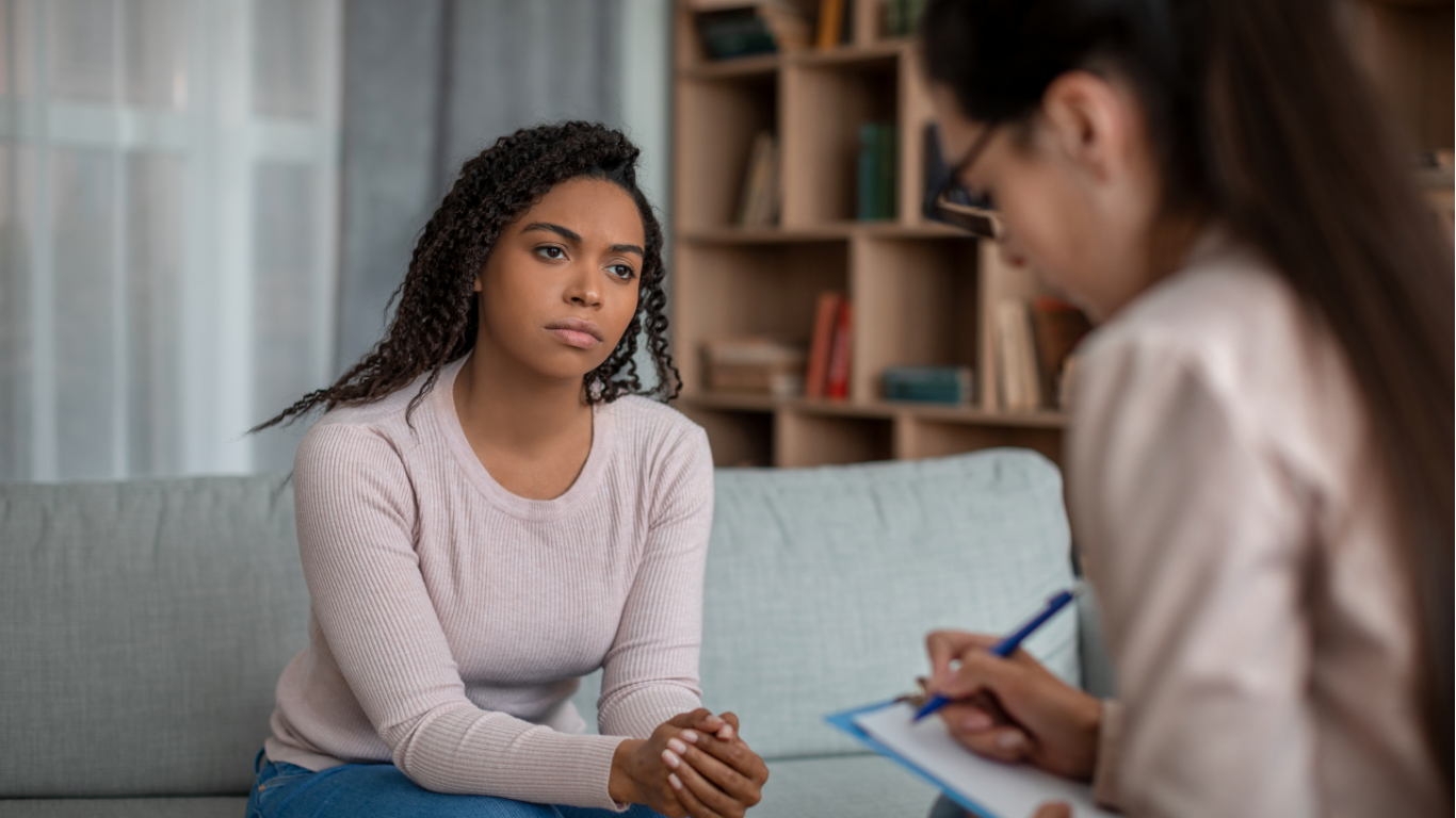 Two people in close conversation. One person clenches hands; the other's hands are open, offering support.