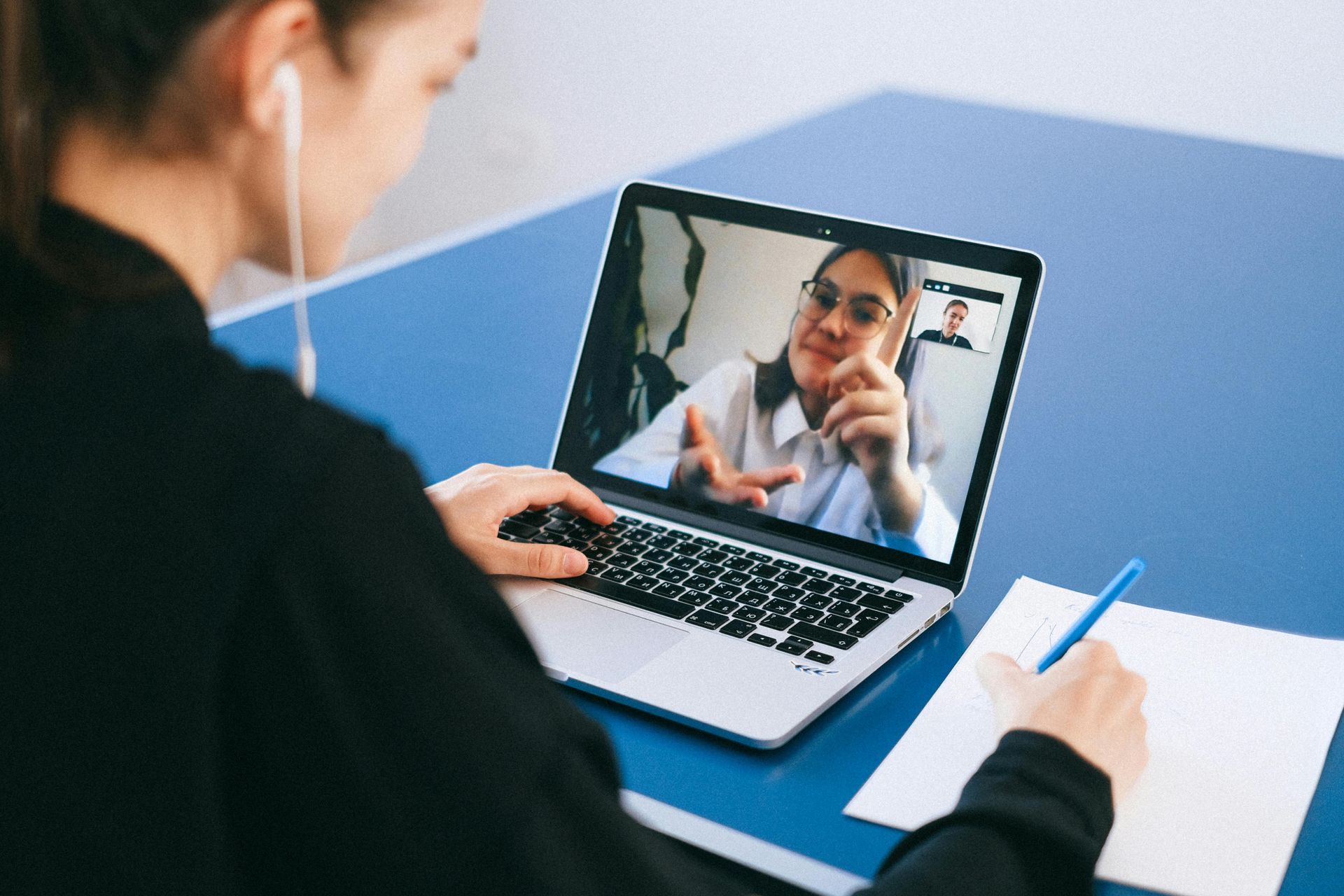 A woman is sitting at a desk using a laptop computer for mental health counseling.