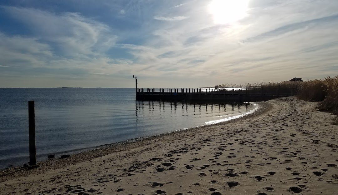 A beach with a pier in the distance and a dock in the water.