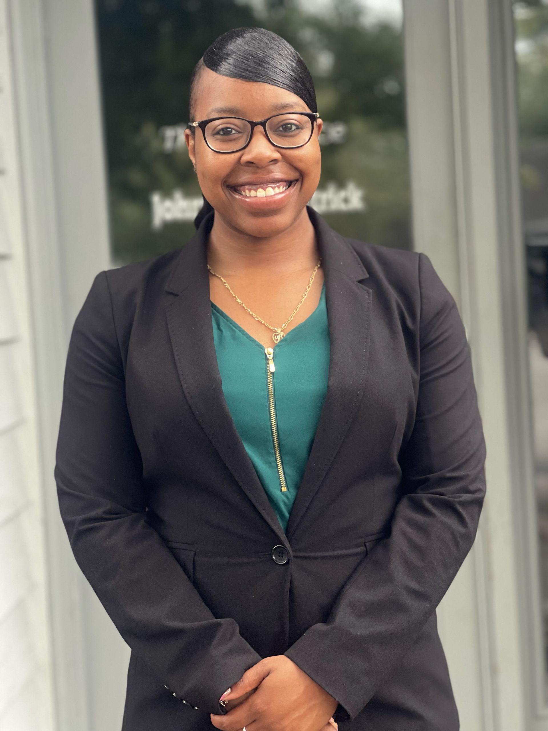 A woman wearing a white jacket and a black sash with scales of justice on it