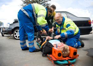 A group of paramedics are helping a woman who is laying on a stretcher.