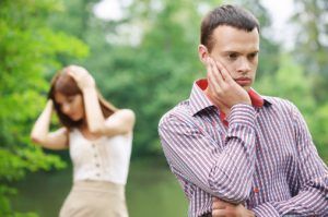 A man and a woman are standing next to each other in a park.