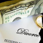 torn divorce decree and cash, with wedding ring