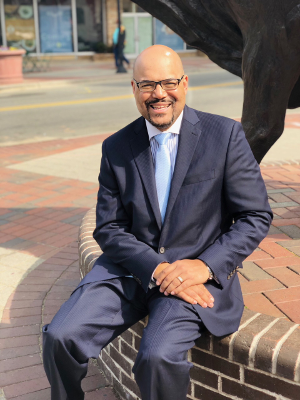 A man in a suit and tie is sitting on a brick wall.