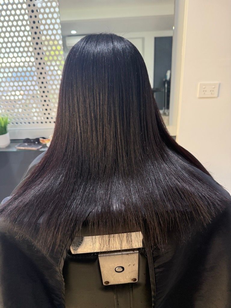 A Woman is Sitting in a Chair With Her Hair in a Bun — Azure Hair in South Mackay, QLD