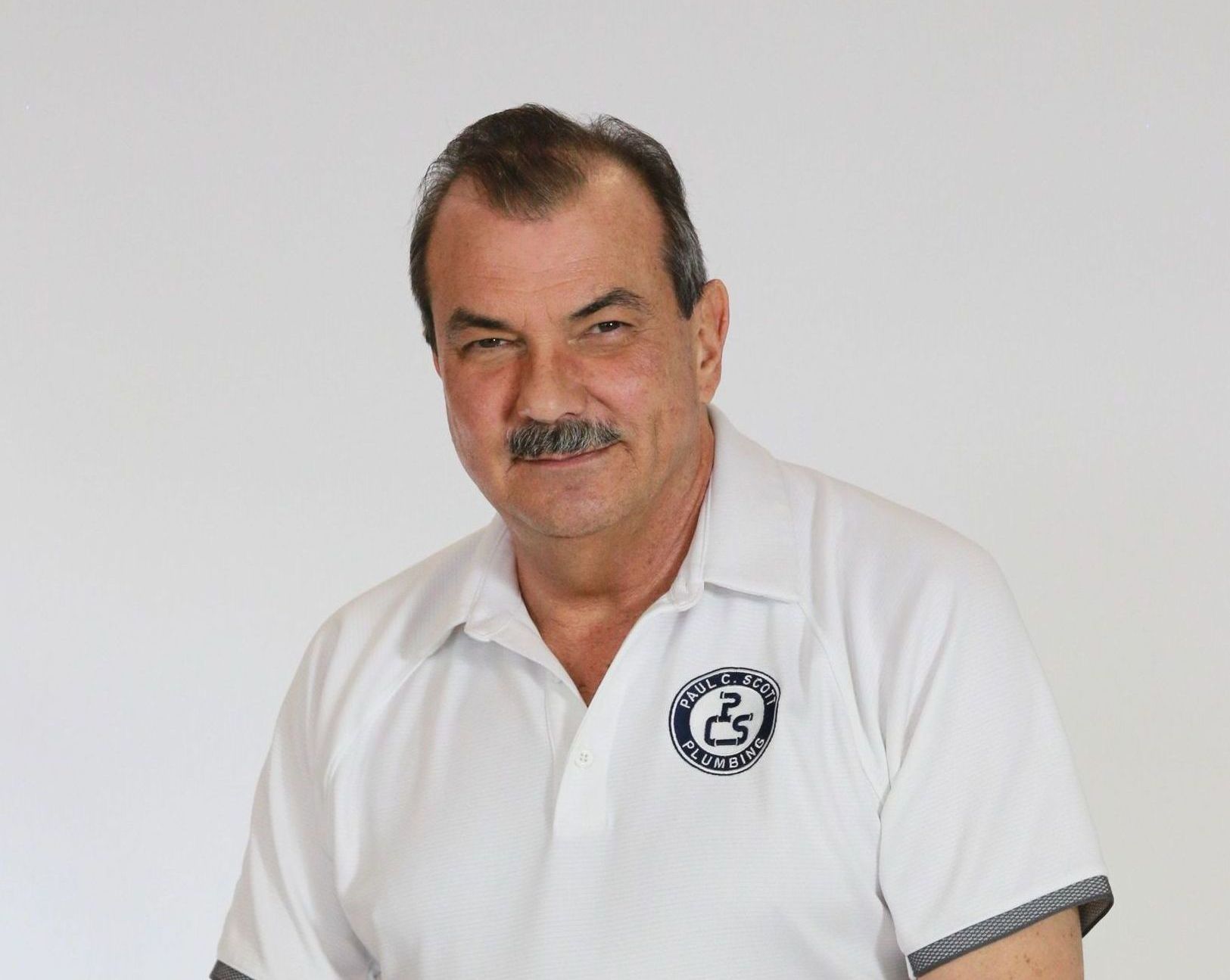 A man with a mustache wearing a white polo shirt