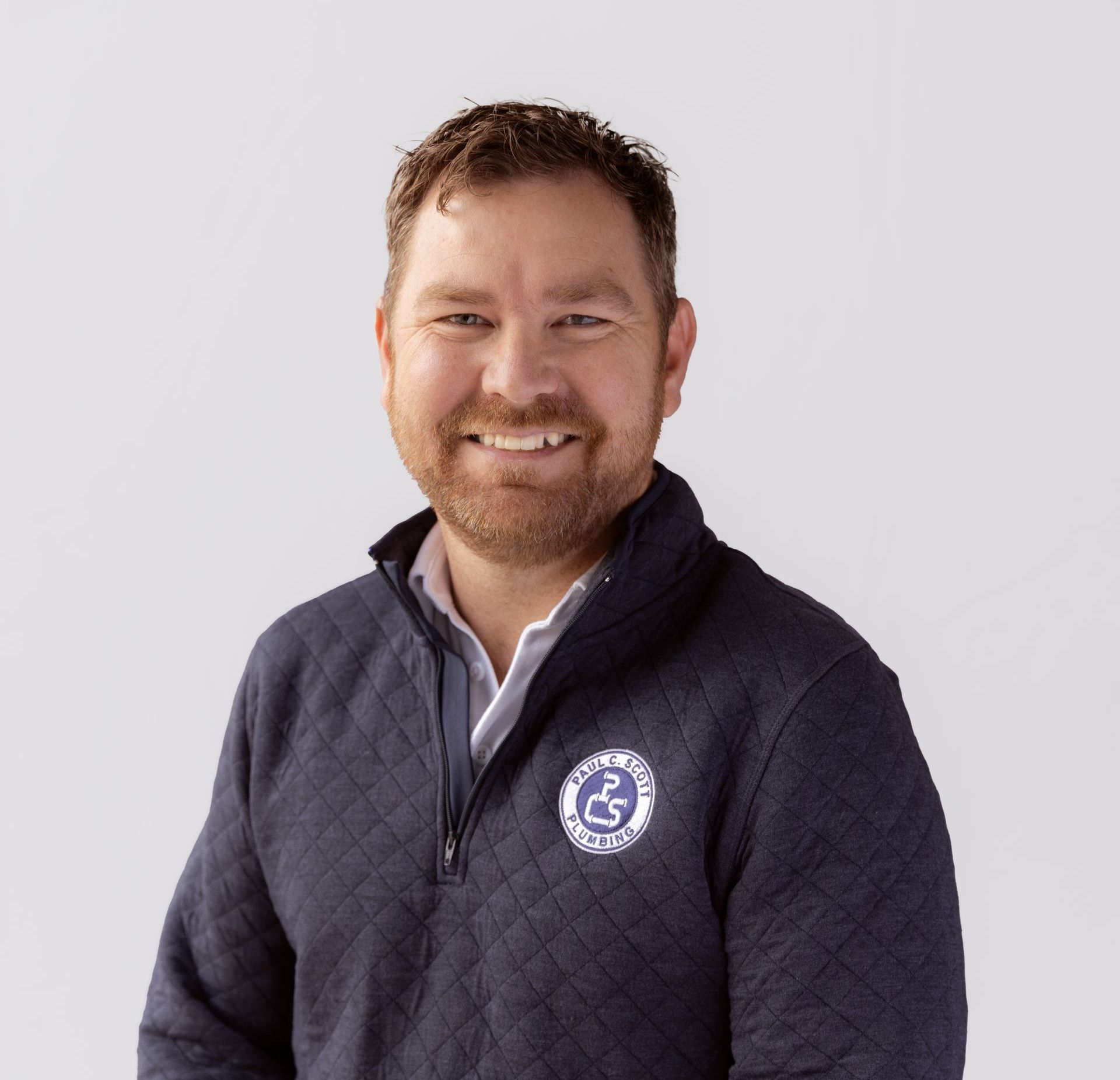 A man with a beard is wearing a white polo shirt
