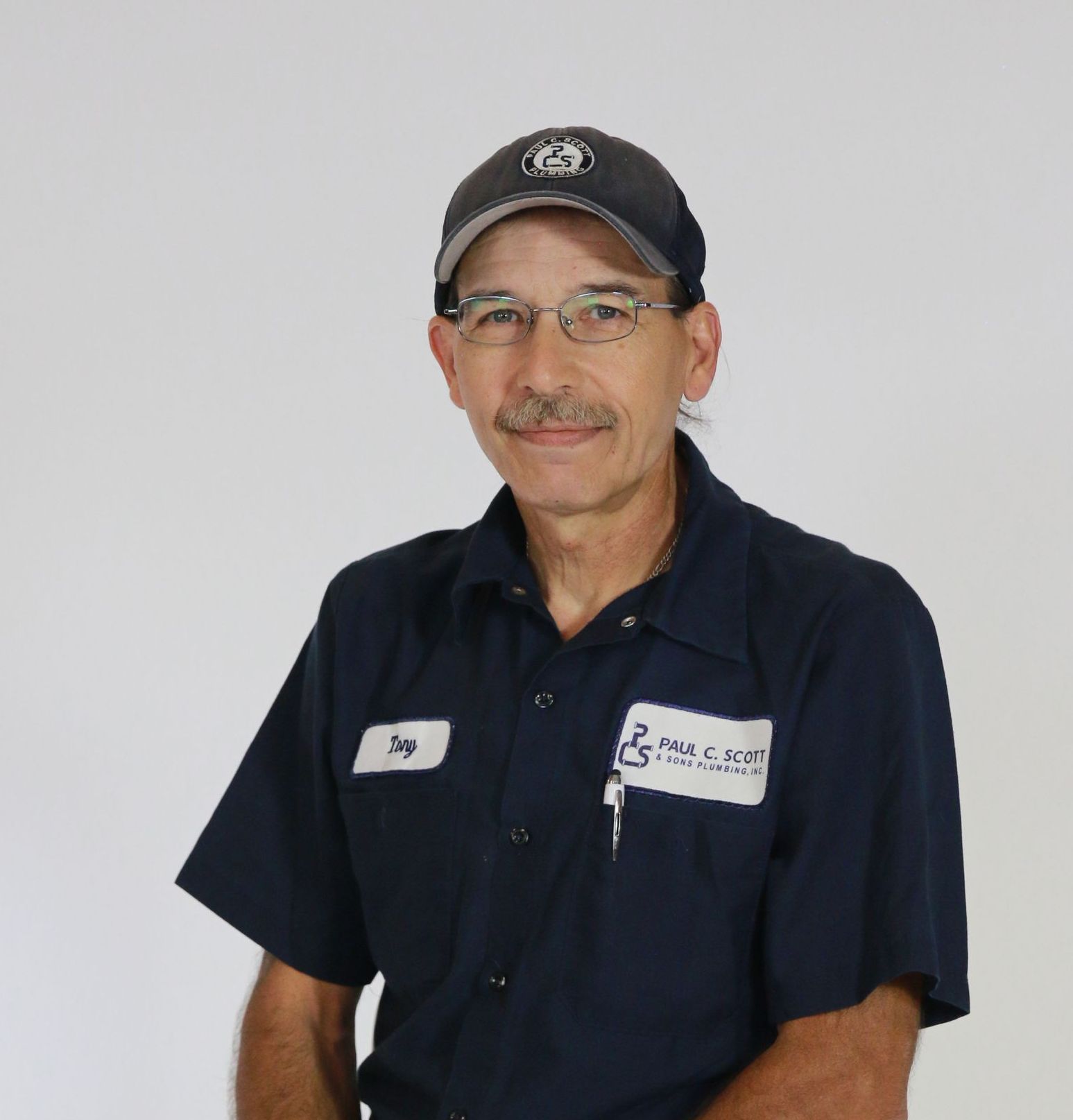 A man wearing a hat and a shirt with a tag that says ' t.g. ' on it
