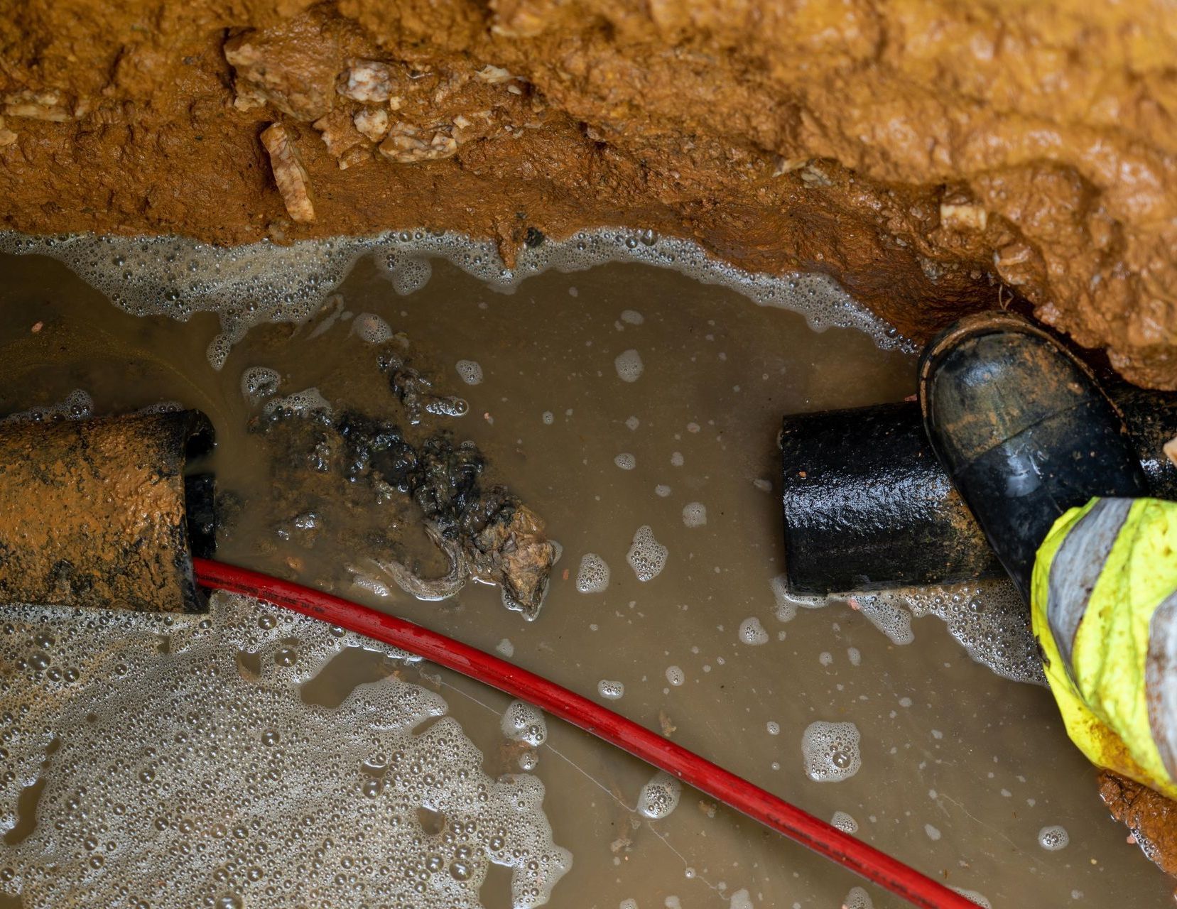 A person is laying pipes in a trench.