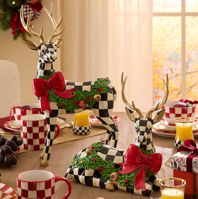 Checkered reindeer figurines with red bows and gold antlers on a decorated table.