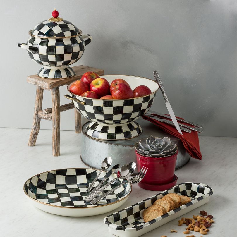 Black and white checkered serving dishes with fruit and cookies.