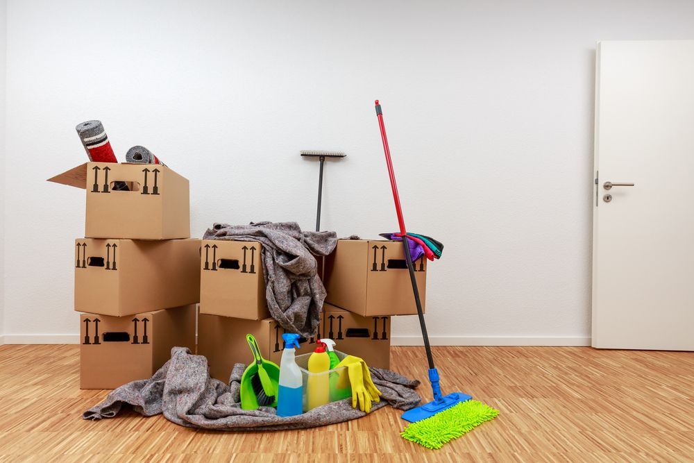 A room filled with cardboard boxes and cleaning supplies.