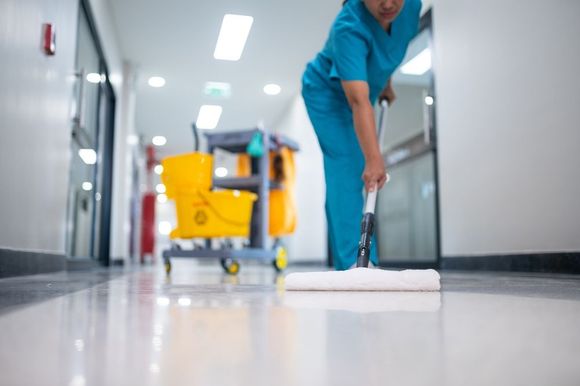 A nurse is mopping the floor of a hospital hallway.